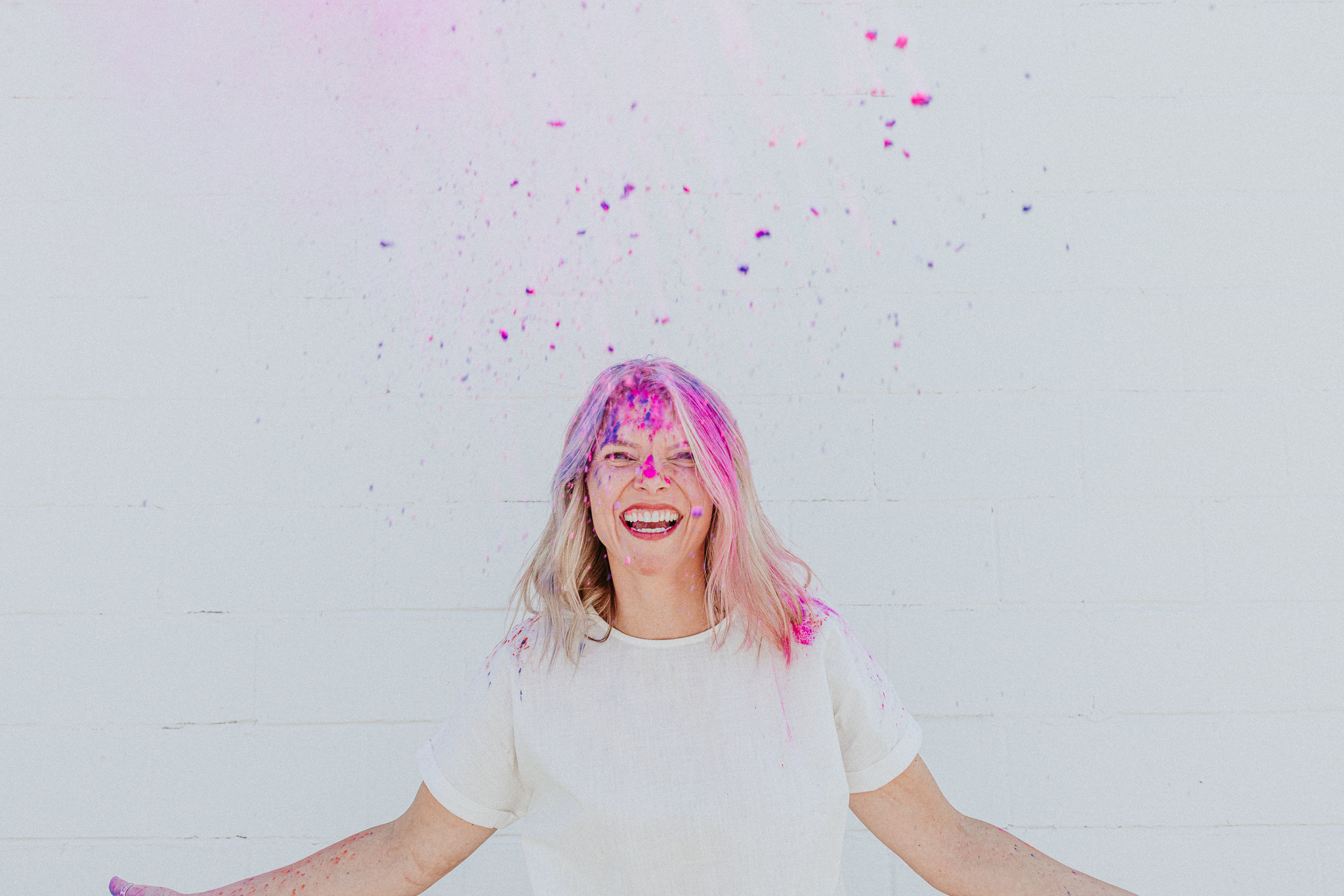 christian health coach celebrating weight loss with white background and pink paint powder in the air